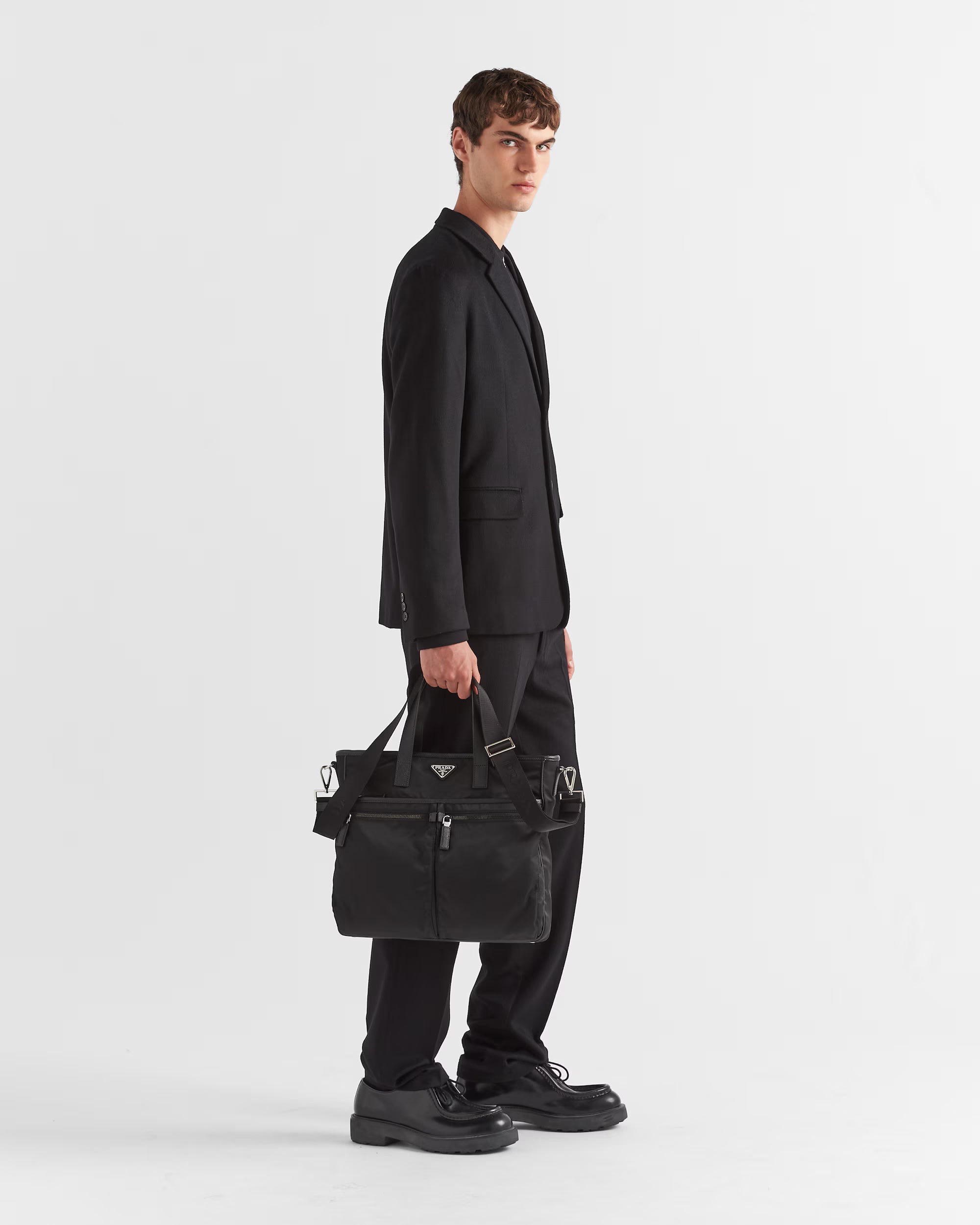 Man holding a black leather briefcase against a white background.